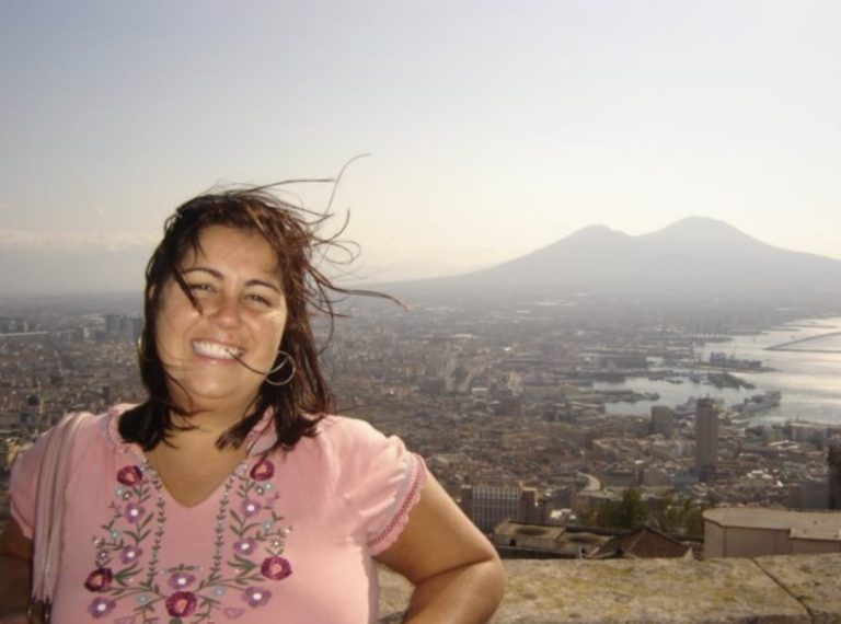 Daniela Pescuma laughing on a rooftop in Naples in 2008, with Mount Vesuvio and the city visible behind her