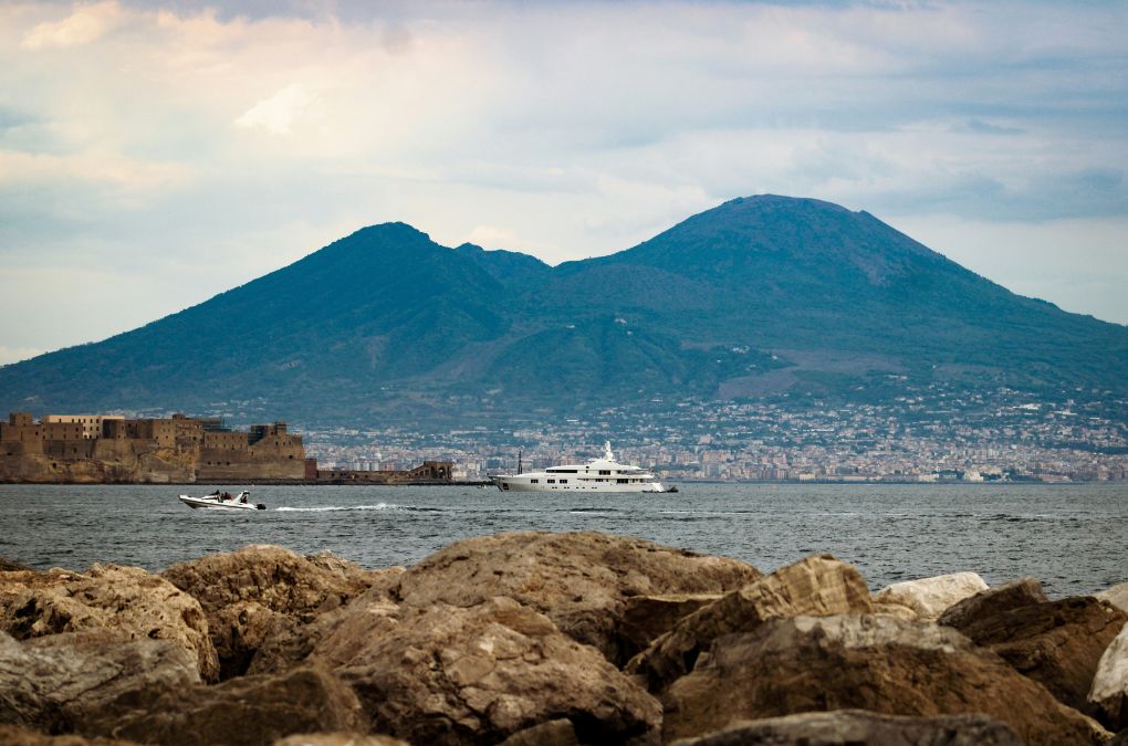 A luxury yacht on the Bay of Naples with Mount Vesuvius and Castel dell'Ovo in the background