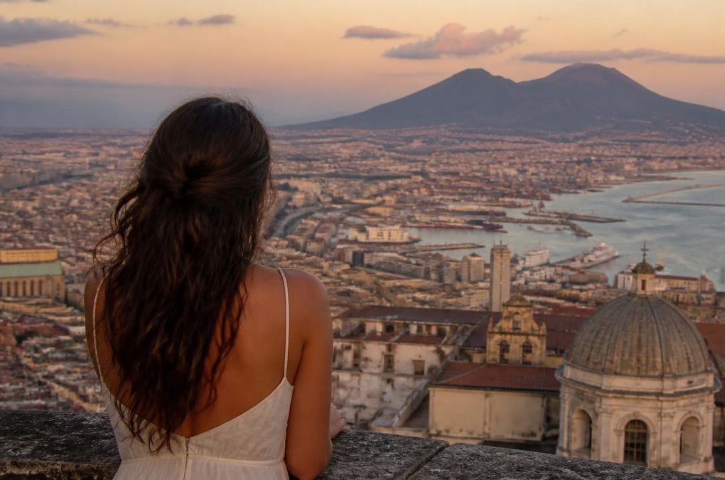a woman seen from behind, alone, looking out over the Bay of Naples with Vesuvio in the background