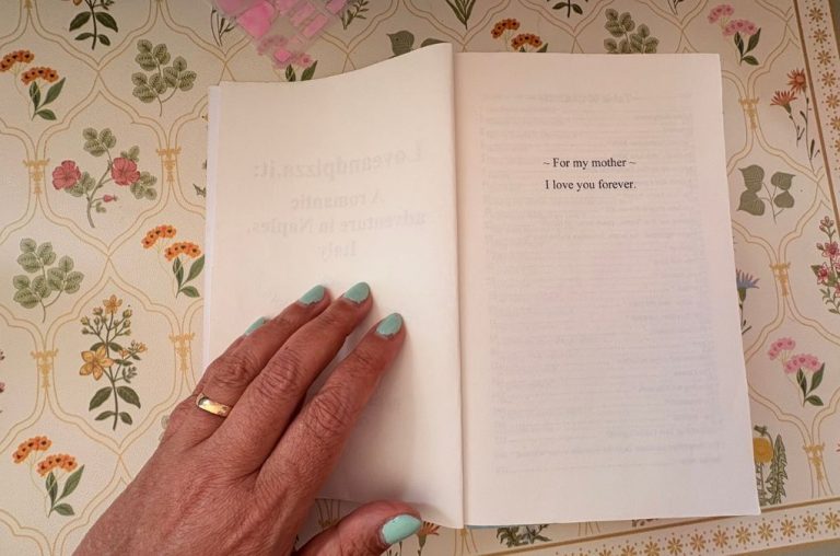 A hand resting on the open dedication page of Loveandpizza.it, reading "For my mother, I love you forever"