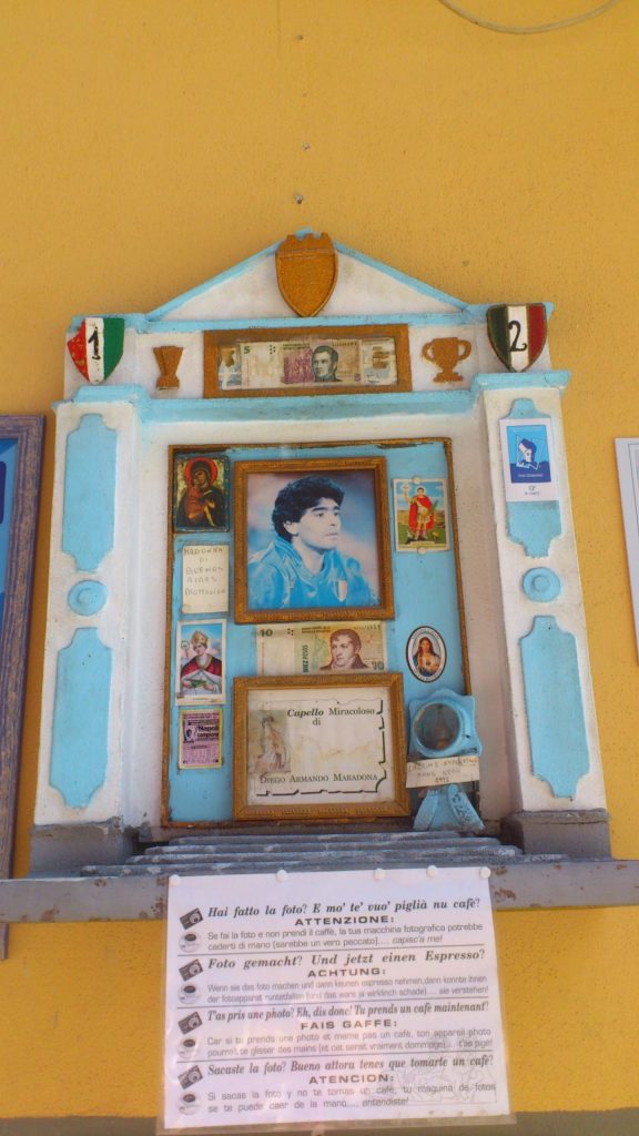 A shrine to Diego Maradona in Naples containing a framed photo, a lock of his hair and religious icons