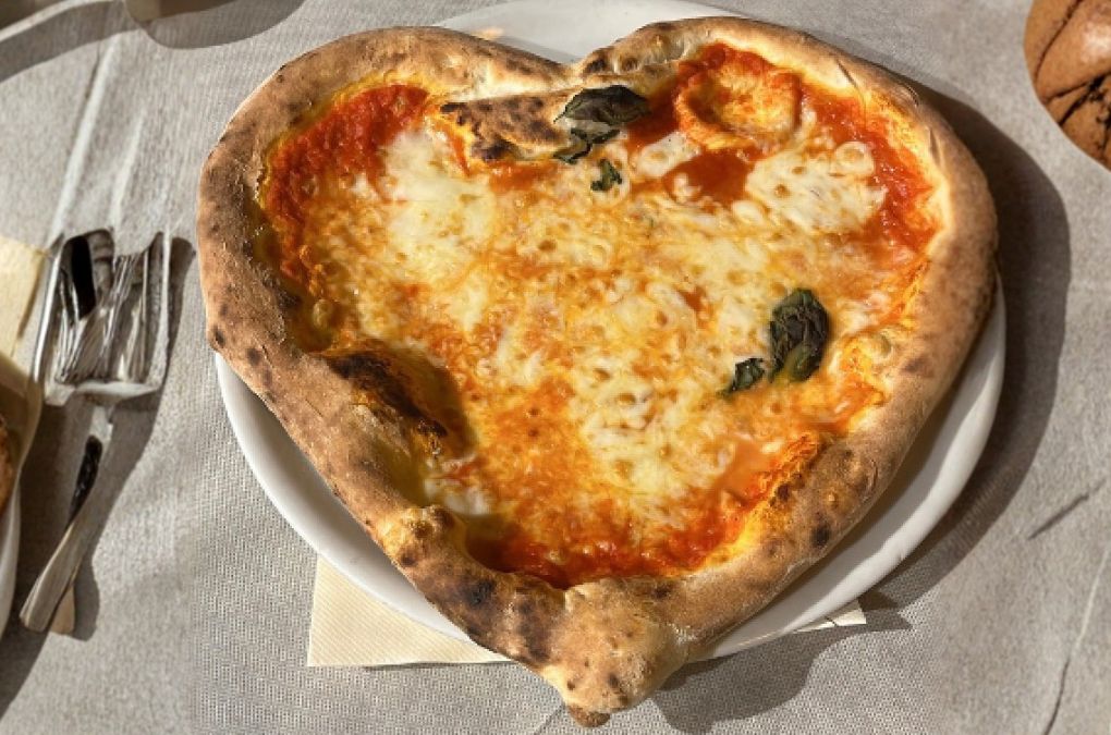A heart-shaped Neapolitan Margherita pizza on a white plate