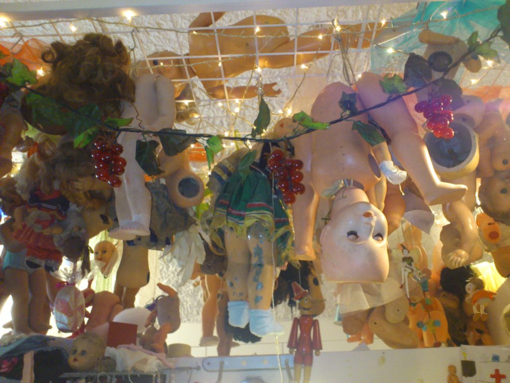 Rows of dolls hanging inside the Ospedale delle Bambole in Napoli, lit by fairy lights