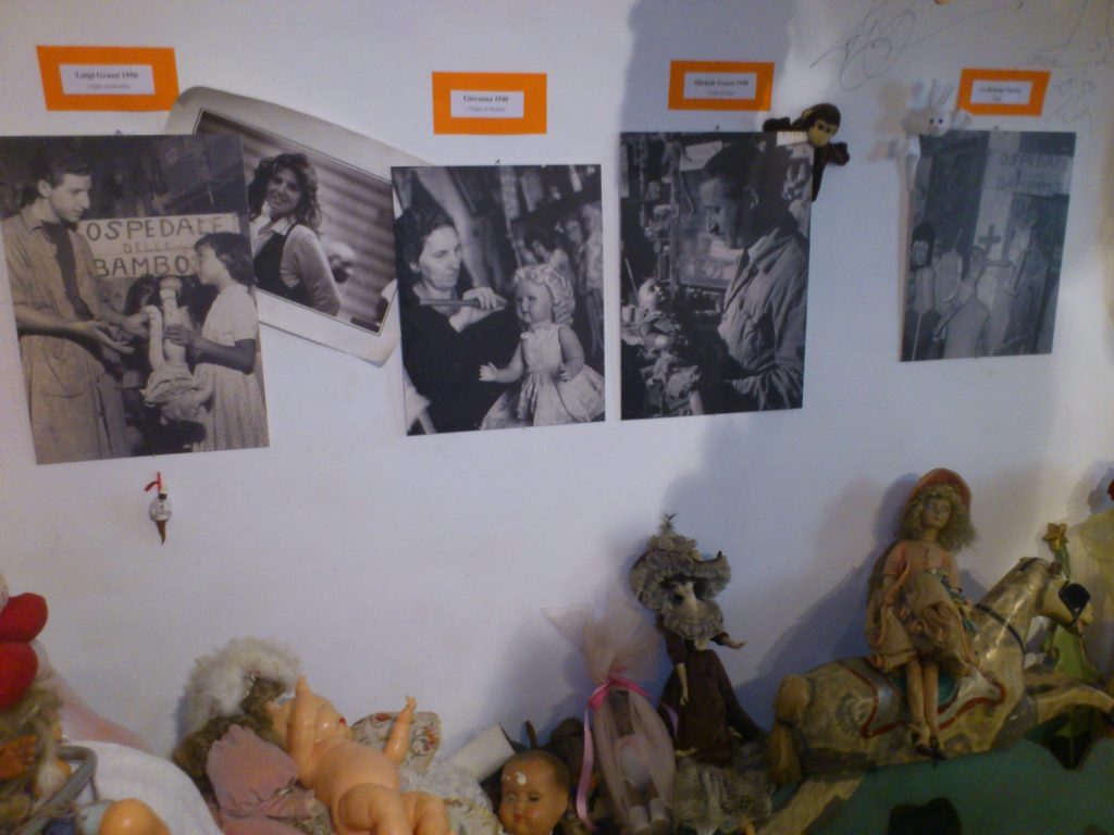 Black-and-white family photographs on the wall of the Ospedale delle Bambole, documenting four generations of doll restorers